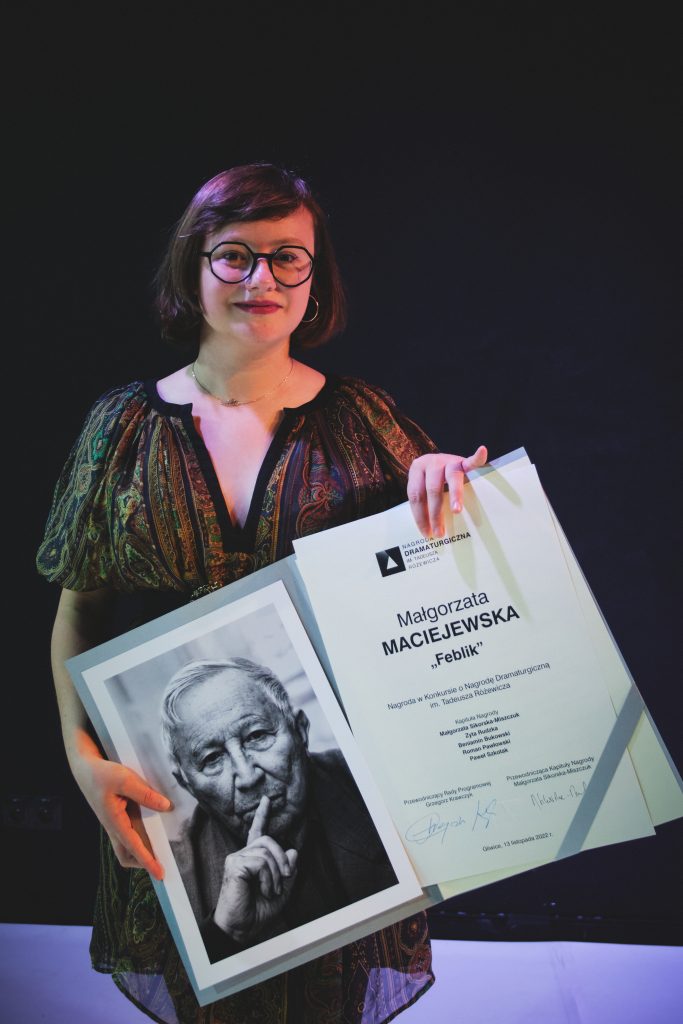 Kobieta trzymająca w ręku teczkę ze zdjęciem Tadeusza Różewicza oraz dyplom. Zwyciężczyni konkursu. 